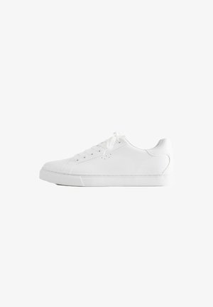 Witte lage sneaker met veters, glad leren bovenwerk en een platte rubberen zool, vanaf de zijkant op een witte achtergrond.