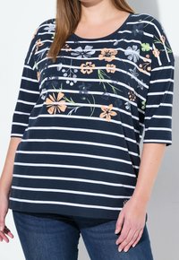 Marinrandig t-shirt med blommönster i nyanser av persika, vitt och grönt. Har rund halsringning och trekvartslånga ärmar.