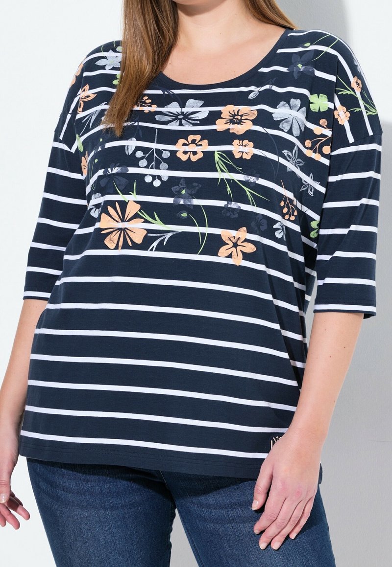 Marinrandig t-shirt med blommönster i nyanser av persika, vitt och grönt. Har rund halsringning och trekvartslånga ärmar.