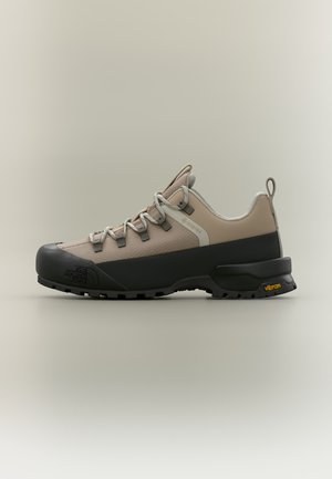 Widok z boku beżowo-czarnego buta trekkingowego z cholewką Gore-Tex, podeszwą Vibram i sznurowanym fasonem.