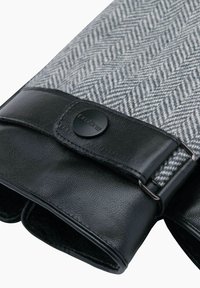 Graues Stoffgewebe mit Fischgrätenmuster und schwarzen Lederelementen. Verfügt über einen Druckknopfverschluss und eine weiche, strukturierte Innenauskleidung. Rechteckige Form für Funktionalität.