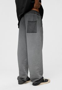 Grijze sweatpants met een trekkoord in de taille, een loose fit en een enkele patch pocket op de achterkant. De stof heeft een zachte, gestructureerde uitstraling.