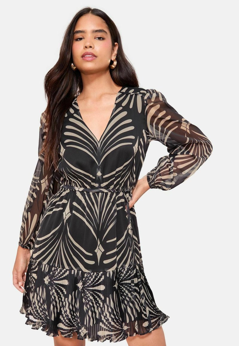 Rochie neagră cu mâneci lungi, cu decolteu în V adânc, decorată cu un model bej cu frunze. Material fluid din chiffon cu tiv ondulat și talie strânsă.