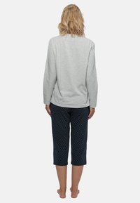 Lichtgrijze lange mouwen top met ronde hals, gecombineerd met marineblauwe cropped broek met witte stippen. Zachte, comfortabele stof.