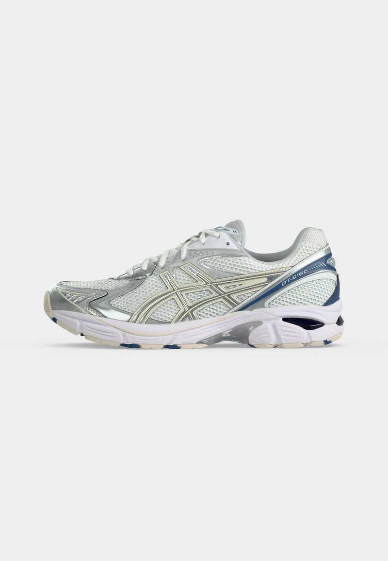 Zapatilla deportiva blanca y plateada con parte superior de malla, cierre de cordones y detalles azules en el talón y la suela, mostrada de lado.