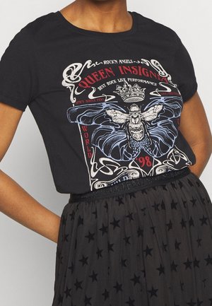 Sort bomulds t-shirt med et grafisk tryk, der viser en sommerfugl, dekorativ tekst og en krone, rund halsudskæring, båret med en nederdel med stjernemønster.