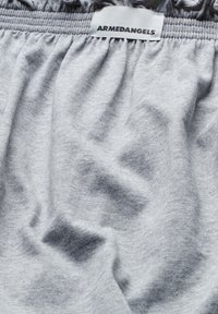 Gray cotton fabric with a soft texture, featuring gathered elastic waist and a label that reads "ARMEDANGELS." Subtle variations in shade.