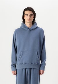 Hoodie bleu en mélange de coton, avec une poche avant, coupe oversize et capuche réglable avec cordon. Texture douce et poignets côtelés.