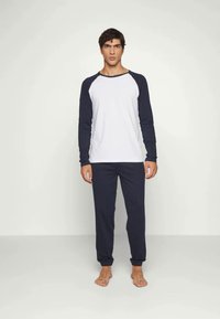 Heren loungewear-set met een witte, lange mouw top en marineblauwe mouwen, gecombineerd met bijpassende marineblauwe broek. De stof lijkt zacht en comfortabel te zijn.