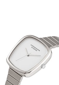 Orologio quadrato in argento con quadrante bianco, design minimalista, cinturino in acciaio inossidabile e una semplice corona sul lato destro.