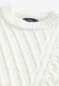 Weißer strukturierter Strickpullover mit einem gerippten Kragen. Verfügt über Zopfmuster und ein sichtbares Etikett im Nackenbereich.