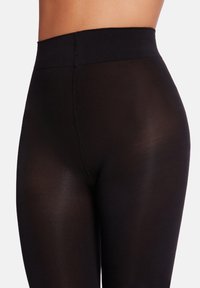 Svarta leggings med hög midja, tillverkade av stretchigt, halvgenomskinligt material. Har en slät yta och subtila sömnadsdetaljer.