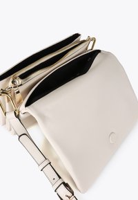 Una borsa a tracolla bianca elegante con una superficie liscia, dotata di due scomparti con zip e di una lunga tracolla regolabile.