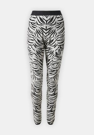 Zwart-witte tijgergestreepte legging met een zwarte tailleband en elastisch materiaal, ontworpen voor een aangesloten silhouet.