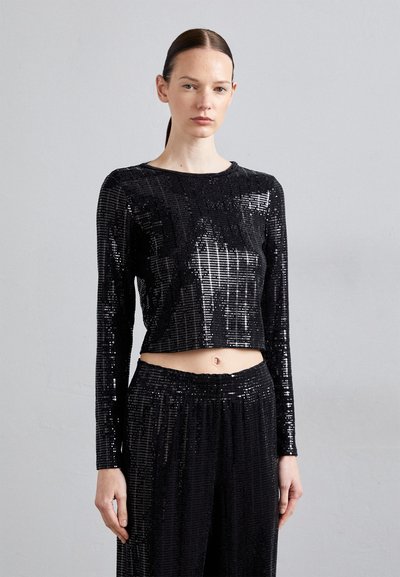 Crop top noir à sequins avec manches longues, surface texturée, décolleté rond et silhouette ajustée, accompagné de pantalons taille haute assortis.