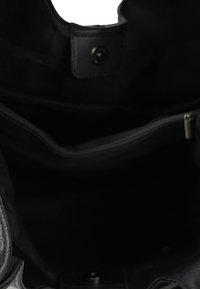 Zwarte stoffen tas interieur met een ritsvak. Kenmerkt zich door een gladde textuur en ronde handvatopeningen. Minimaal beslag, voornamelijk donker.