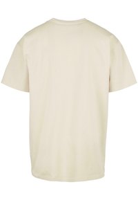 Kortermet t-skjorte med rund hals i lys beige bomull. Glatt tekstur med avslappet passform, uten synlige logoer eller mønstre.