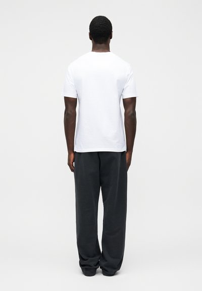 Λευκό κοντομάνικο μπλουζάκι και σκούρο γκρι παντελόνι με άνετη εφαρμογή. Το μπλουζάκι έχει στρογγυλή λαιμόκοψη, ενώ το παντελόνι διαθέτει ελαστική μέση και ίσια πόδια.