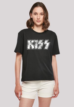 Black cotton t-shirt featuring a distressed white "KISS" logo, short sleeves, round neckline, and a relaxed fit. Paired with white shorts.