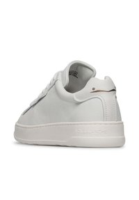 Sneaker in pelle bianca con texture liscia, forma arrotondata e design minimalista. Presenta un logo sottile sul tallone e colletto imbottito.