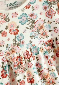 Robe florale avec des fleurs aux couleurs pastel en rouge, rose et turquoise sur un fond crème. Comprend une jupe froncée et un matériau en coton doux.