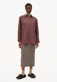 Maroon striped button-up shirt with a chest pocket, paired with a gray knee-length skirt. Black shoes with fringed detail and green socks.
