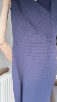 Vestido roxo com textura canalizada, apresentando um design cruzado, padrão texturizado e silhueta justa. O material parece elástico e suave.