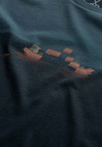 Katoenen t-shirt in donker teal met een vervaagd grafisch ontwerp van cargschip in oranje en bruine tinten, met een zachte textuur en een ronde hals.
