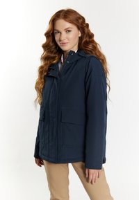 Giacca con cappuccio blu navy, con zip frontale, due grandi tasche anteriori e una texture di tessuto liscia. Presenta un cordino regolabile sul cappuccio.