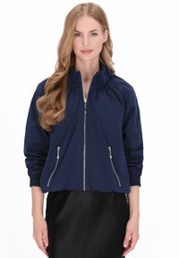 Marineblauw bomberjack met een ritssluiting aan de voorkant, een geplooide halslijn, geribbelde manchetten en twee zijzakken met ritssluiting. Lichtgewicht en met een gladde textuur.