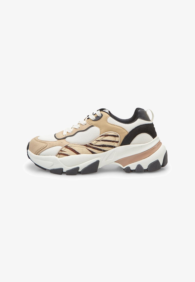Zapatilla gruesa con paneles beige, negro y blanco, cordones blancos, detalle de estampado animal y suela gruesa negra y beige.