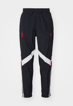 Pantalones deportivos negros con acentos diagonales en rojo y blanco. Cuentan con una cinturilla elástica, cordón y rayas laterales. Fabricados con tela ligera.