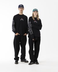 Sorte langærmede skjorter med logo prints, parret med løse sorte bukser. En marineblå kasket og en turkis kasket fuldender outfittene.