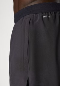 Svarte treningsshorts med en pustende nettinglinning, med en fukttransporterende DRYCELL-logo og sideslisser for økt bevegelighet.