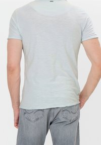 Světle modré tričko s krátkým rukávem, vyrobené z měkké tkaniny, s mírně přiléhavým střihem a jemnými švy na okraji.