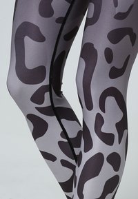Grå leggings med ett svart oregelbundet leopardmönster, tillverkade av ett slätt, stretchigt material med en elegant sid söm detalj.