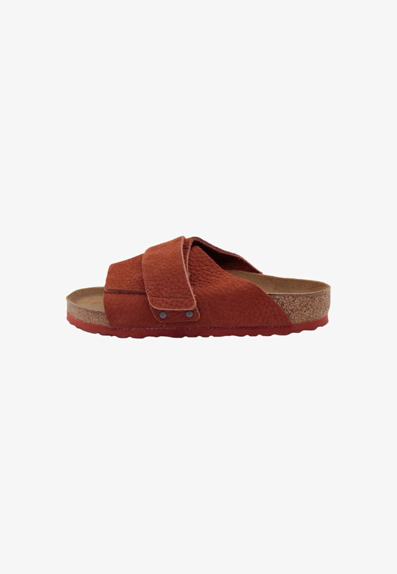Red suede slide sandal with a textured upper, cork midsole, and rubber outsole. Features a wide cross strap and metal hardware accents.