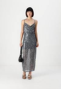 Rochie maxi cu imprimeu de leopard, cu un decolteu drapat, material transparent, bretele fine și o siluetă ajustată. Asortată cu accesorii negre.