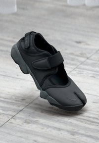 Čierna atletická obuv s rozdeleným dizajnom prstov, textúrované sieťové bočné panely, nastaviteľný suchý zips a polstrovaná podrážka pre pohodlie.