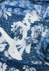 Tela azul con patrón floral y acentos blancos, que presenta una textura suave y una mezcla de tonos que crean profundidad y contraste en el diseño.