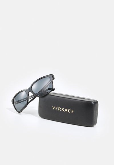 Ochelari de soare negri Versace cu lentile întunecate, având un design îndrăzneț al ramei. Însoțiți de o carcasă elegantă neagră cu litere aurii.