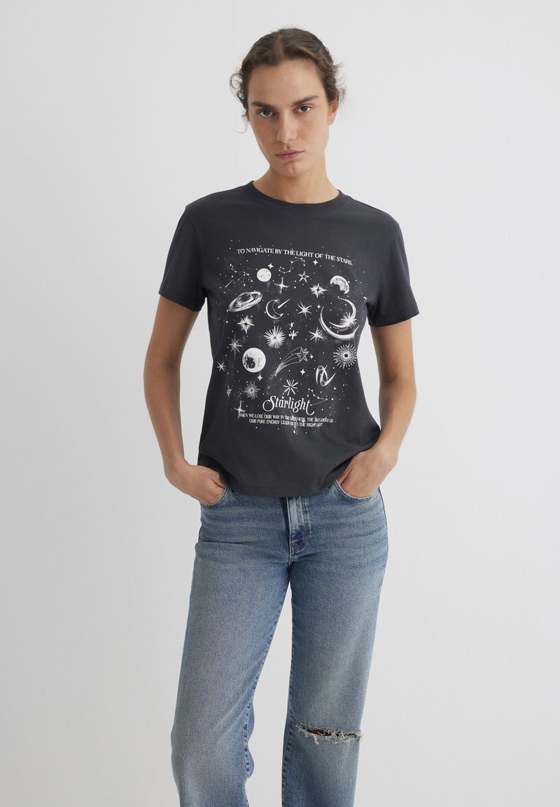 Short-sleeve, dark gray cotton t-shirt featuring a celestial print in white, including planets and stars, with text below the design.