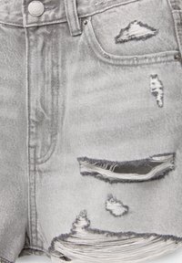 Short en jean gris clair avec plusieurs détails effilochés et déchirés à l'avant, incluant une grande déchirure horizontale près de l'ourlet et des petites déchirures au-dessus.