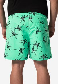 Mintgröna badshorts med ett mönster av svarta palmblad. Har en elastisk midja och en bakficka med knäppe.