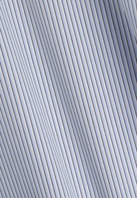 Tissu bleu clair avec de fines rayures verticales noires créant un motif lisse et fluide à la surface.