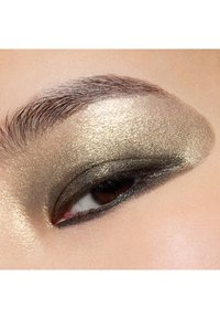 Close-up of an eye with gold and black eyeshadow, featuring a shimmery finish and defined eyeliner, highlighting smooth skin texture.