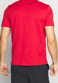 Czerwona bawełniana koszulka z krótkim rękawem; posiada okrągły dekolt, miękką teksturę i luźny fason, z gładkim tyłem.