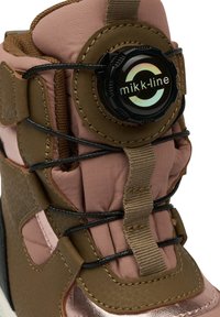 Bota impermeable para niños en marrón y rosa con parte superior acolchada, detalles texturizados, cordones negros y un mecanismo de cierre ajustable circular.