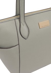 Lichtgrijze leren tote bag met gouden rits, logo plaat en een soepele textuur. Beschikt over twee stevige handvatten en een voorvak.