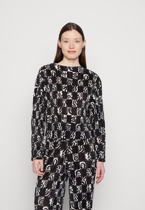 Conjunto em preto e branco com um padrão geométrico, apresentando mangas compridas e decote redondo, feito de um tecido texturizado com pregas.